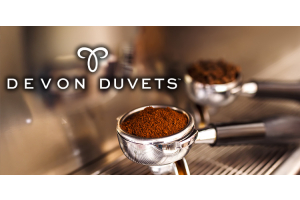 Devon Duvets logo over a coffee machine portafilter filled with ground coffee.