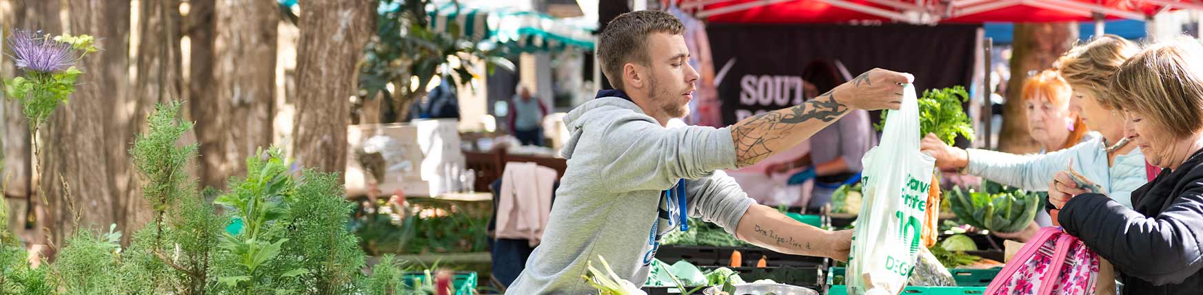 A farmers market with people buying local produce in Devon.