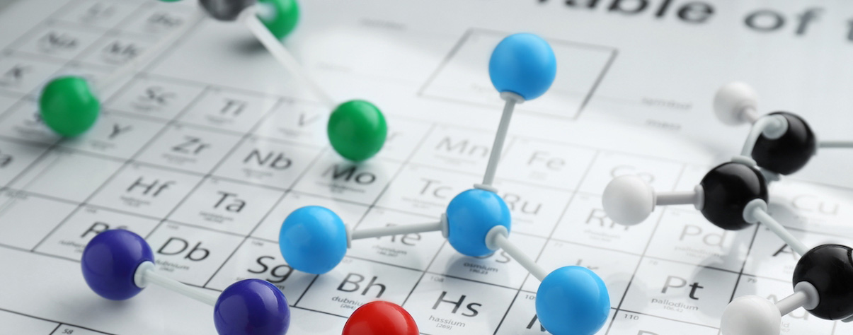 Close-up of a periodic table of elements with colourful molecular models placed on top, representing chemistry and scientific discovery.