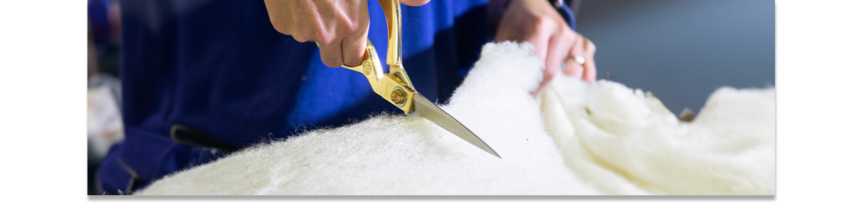 Close-up of artisan using scissors to cut wool, showcasing ethical craftsmanship.