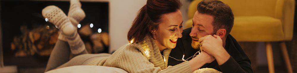 Happy couple relaxing together on a cosy bed, enjoying better sleep with tailored bedding solutions.